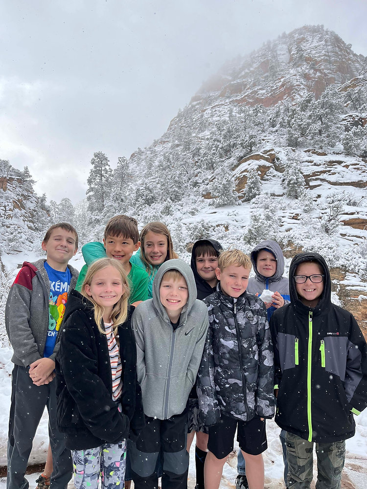 A joyful group of children smiling and posing for a photo in the snowy landscape.