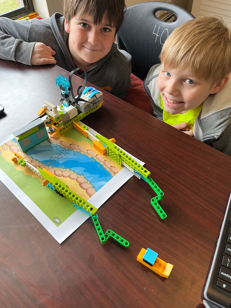Two boys happily building with a Lego set, showcasing their creativity and teamwork.
